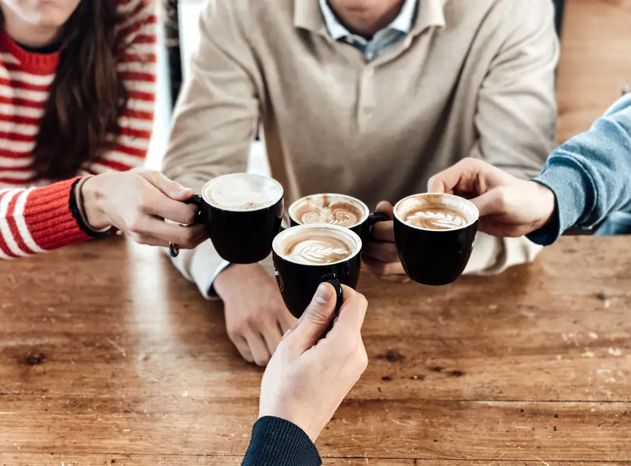 Amici brindano con diversi tipi di caffè al bar, con schiuma artistica e latte macchiato.