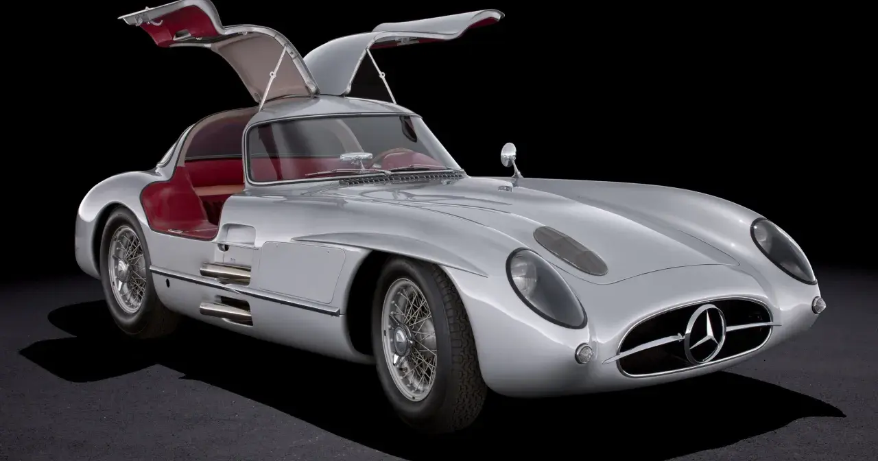 Srebrny Mercedes 300 SL Gullwing z otwartymi drzwiami, czerwone wnętrze, klasyk motoryzacji.