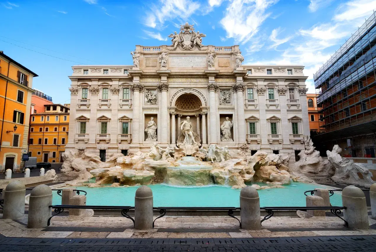 La Fontana di Trevi, con le sue sculture barocche e l'acqua turchese, incanta sotto un cielo azzurro.