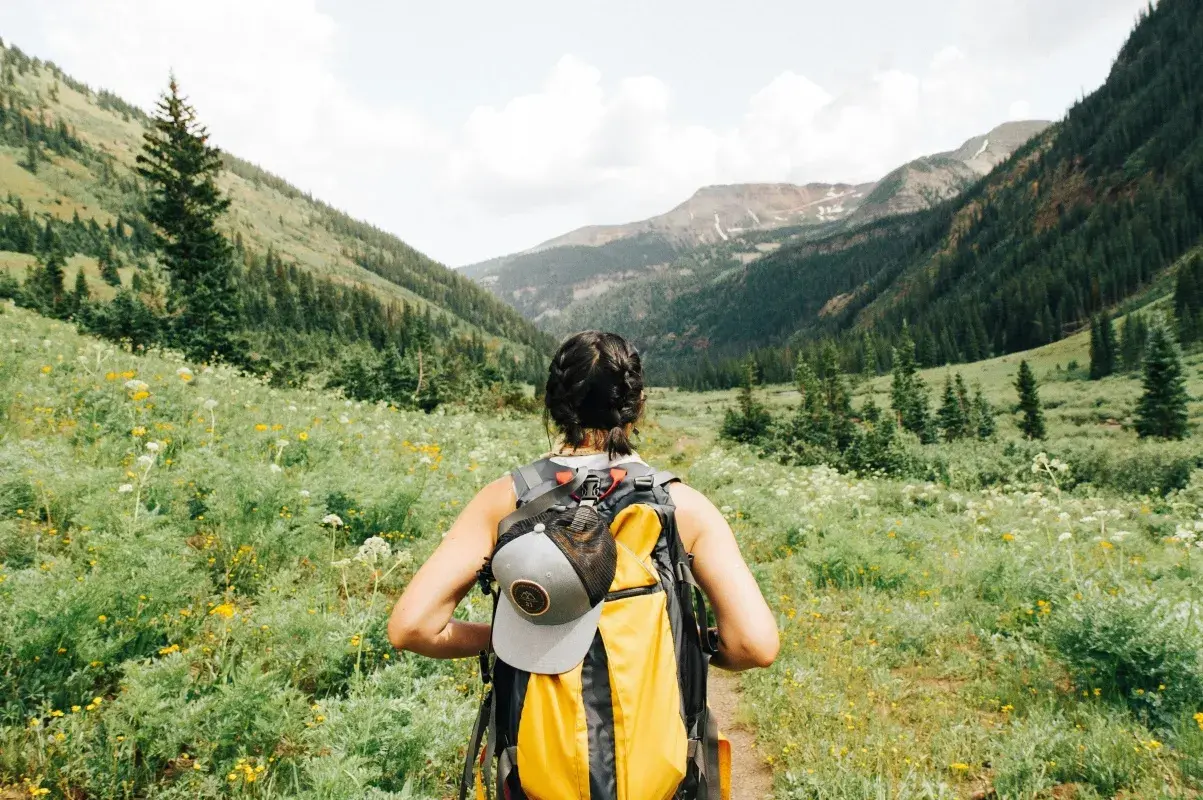 Kobieta z plecakiem wyrusza na szlak. To idealny dzień na trekking, który odróżnia się od zwykłego hikingu.