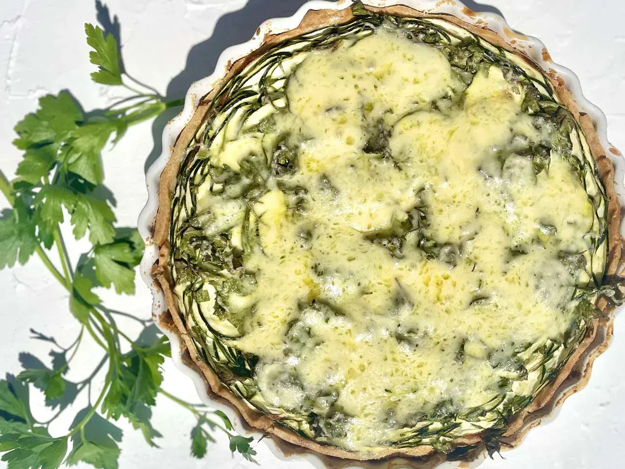 Eine köstliche Zucchini-Quiche mit goldbraunem Teig und einer cremigen Füllung, garniert mit frischer Petersilie.