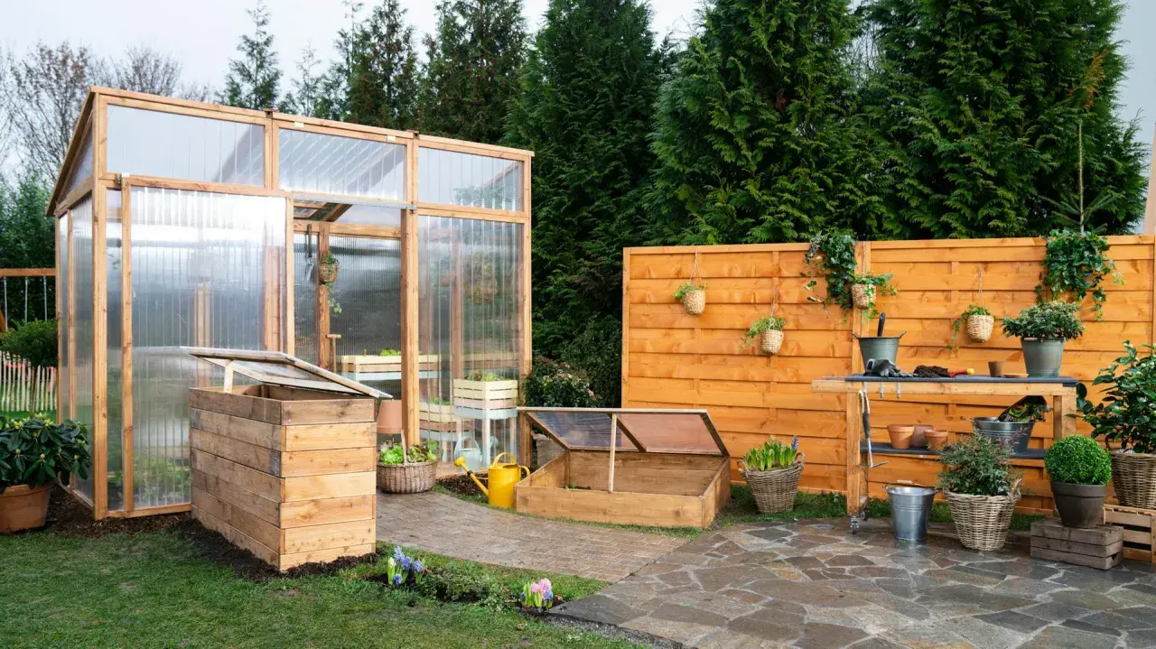 Ein Garten mit einem selbstgebauten Tomatenhaus, Frühbeet und einer Werkbank. Perfekt für alle, die ihr Tomatenhaus selber bauen möchten.