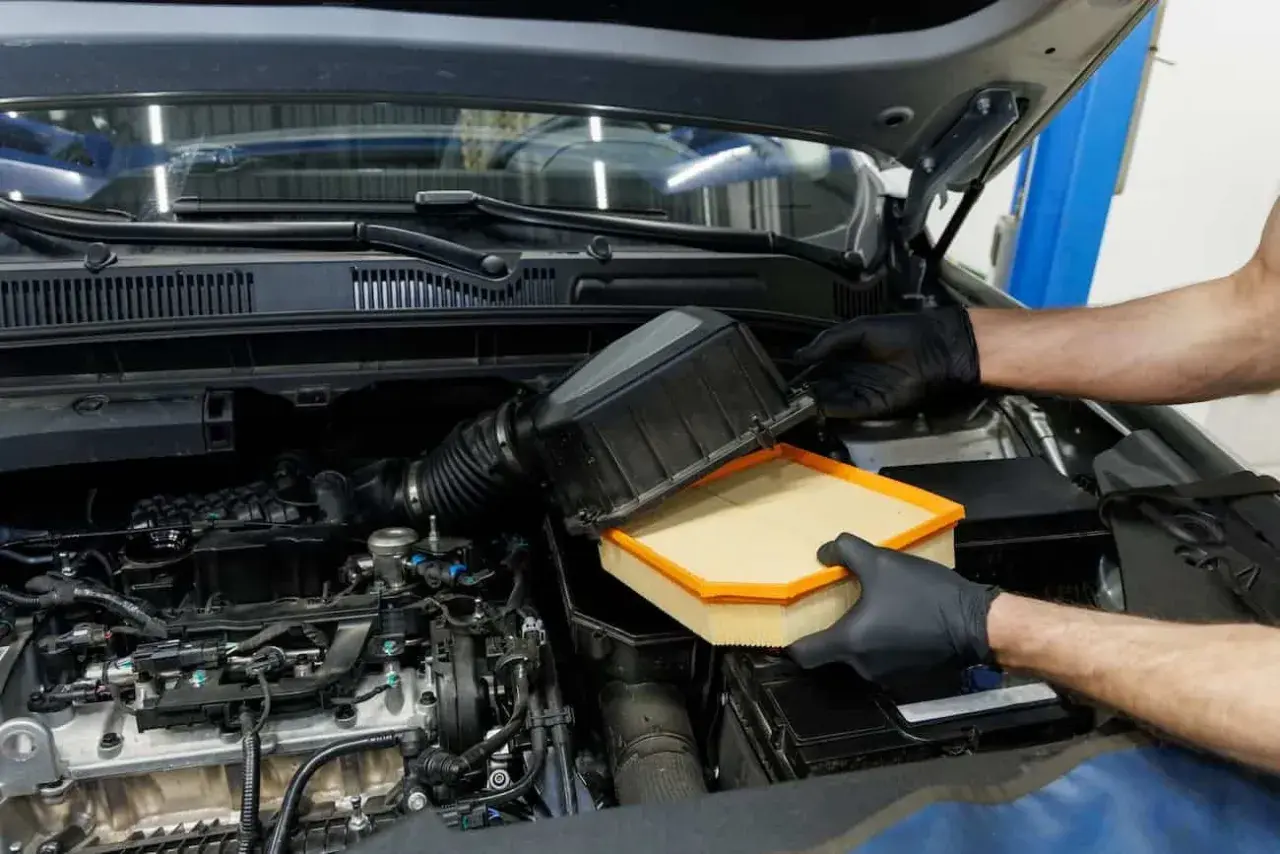 Manos enguantadas cambian el filtro del aire del coche. Este componente es vital para el motor, ya que el filtro del aire ¿para qué sirve? Limpia el aire que entra.
