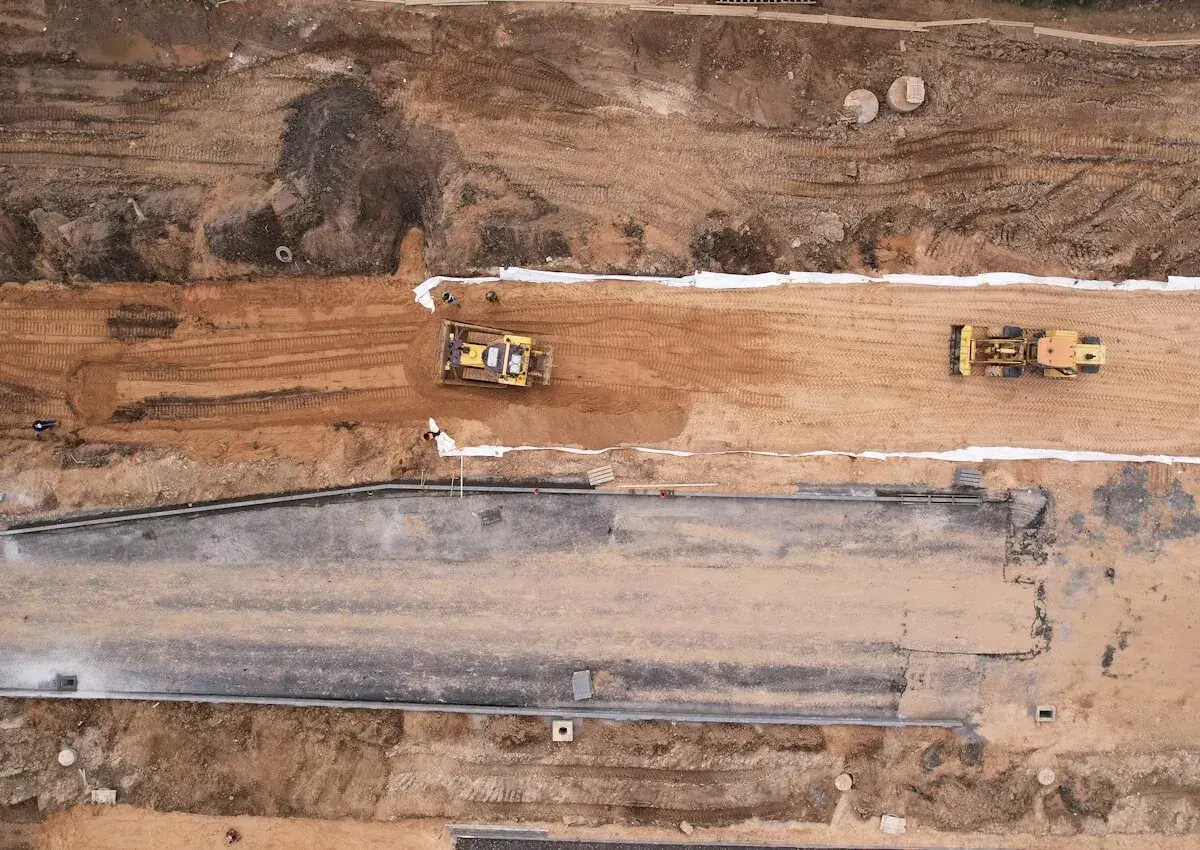 Bagger verdichten die **hydraulisch gebundene Tragschicht** auf einer Baustelle.