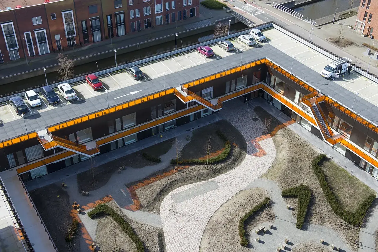 Moderne Architektur mit begrüntem Innenhof und Parkplätzen. Die Dachpappe wurde begehbar gemacht und dient als Parkfläche.