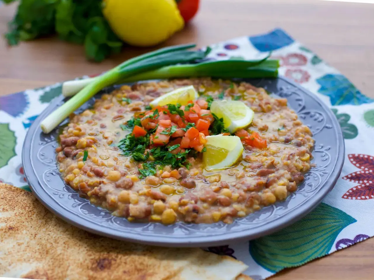 En tallrik med en mustig foul-rätt, toppad med tomat, persilja och citron. Ett utsökt recept för en smakrik måltid.