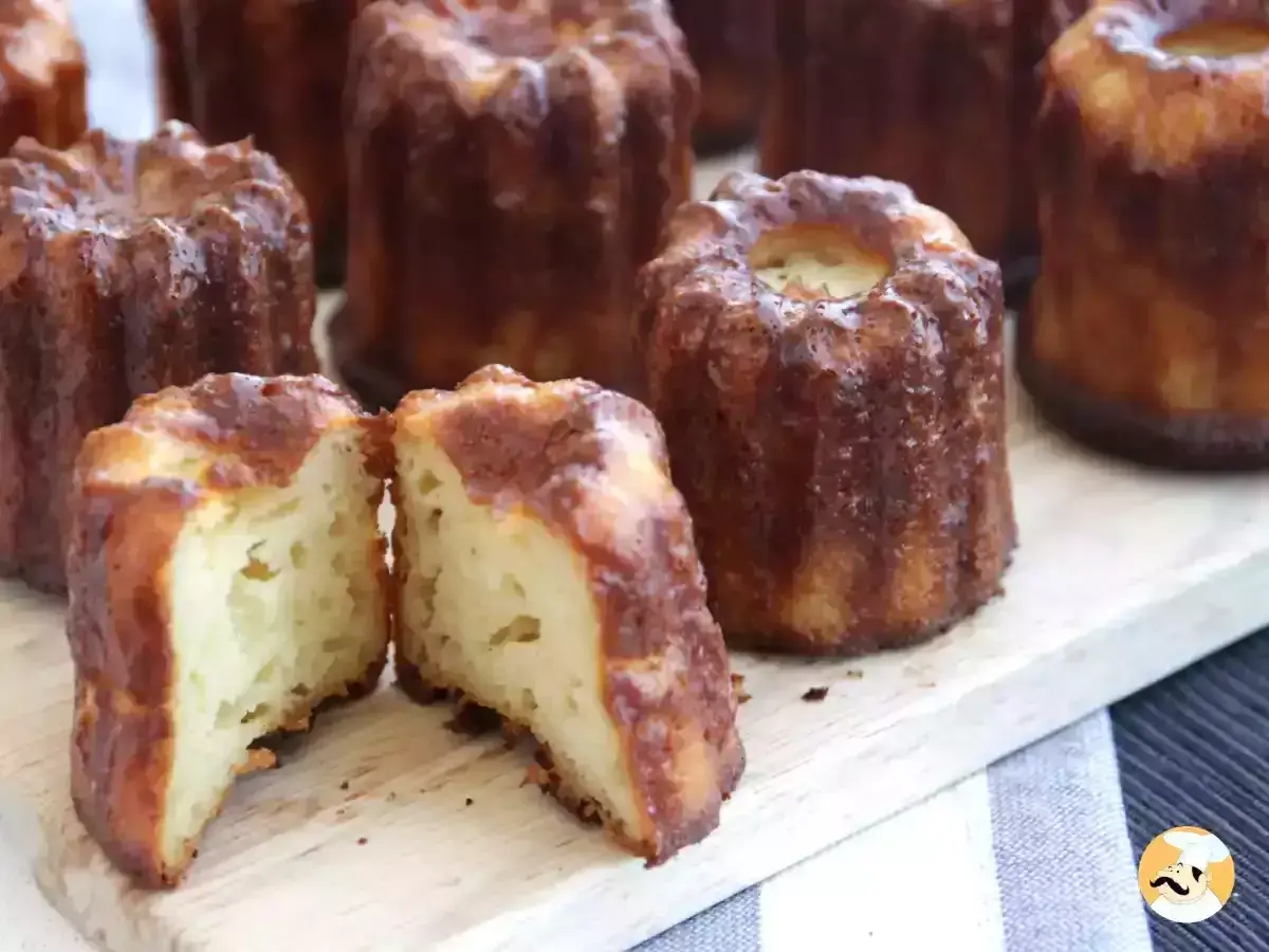 Délicieux cannelés dorés, un classique de la recette cannelés. L'un est coupé en deux, révélant sa mie moelleuse.