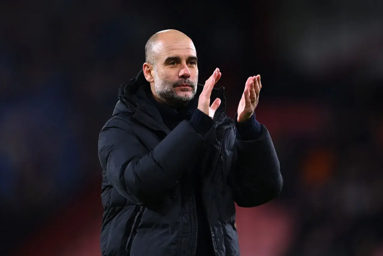 Pep Guardiola, znany z tego, że prowadzone drużyny osiągają sukcesy, klaszcze na boisku w zimowej kurtce.