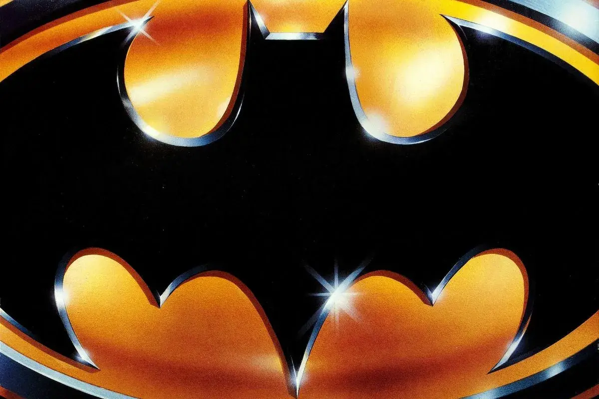 Logo Batmana z 1989 roku na tle gradientu pomarańczowo-żółtego.