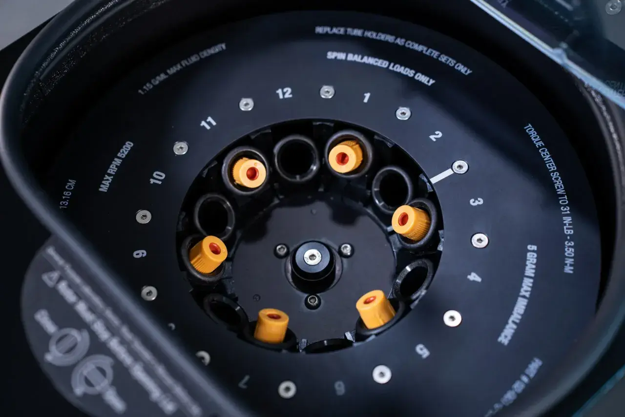 Rotor de centrifugeuse avec des tubes à essai orange. Indique "MAX RPM 5200" pour la centrifugation.