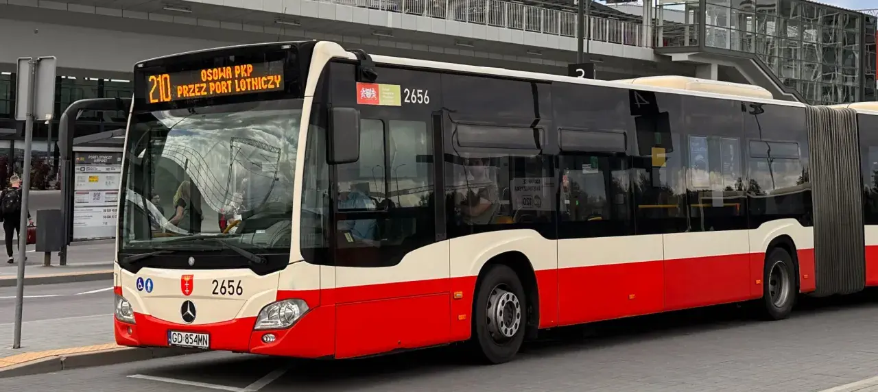 Autobus linii 210 "Przez Port Lotniczy" czeka na pasażerów na przystanku.