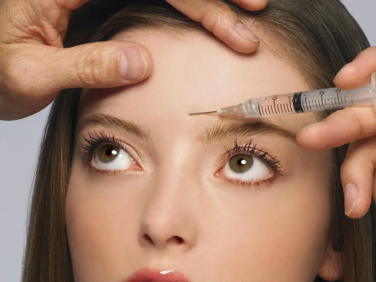 Nahaufnahme einer Frau, der Botox in die Stirn injiziert wird. Mögliche botox spätfolgen im Blick.