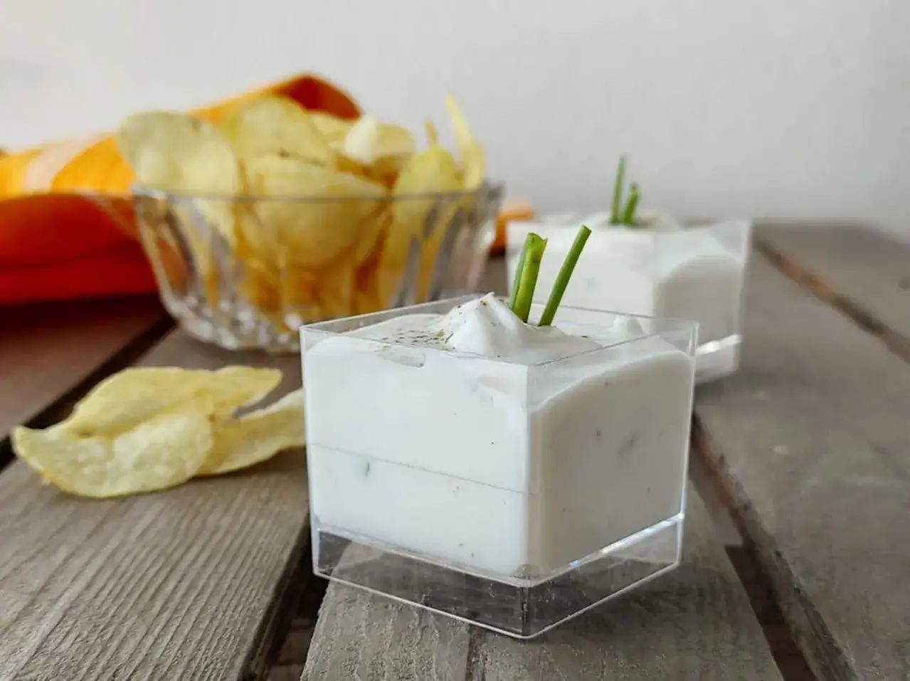 Salsa yogurt cremosa, guarnita con erba cipollina, pronta per accompagnare patatine croccanti.