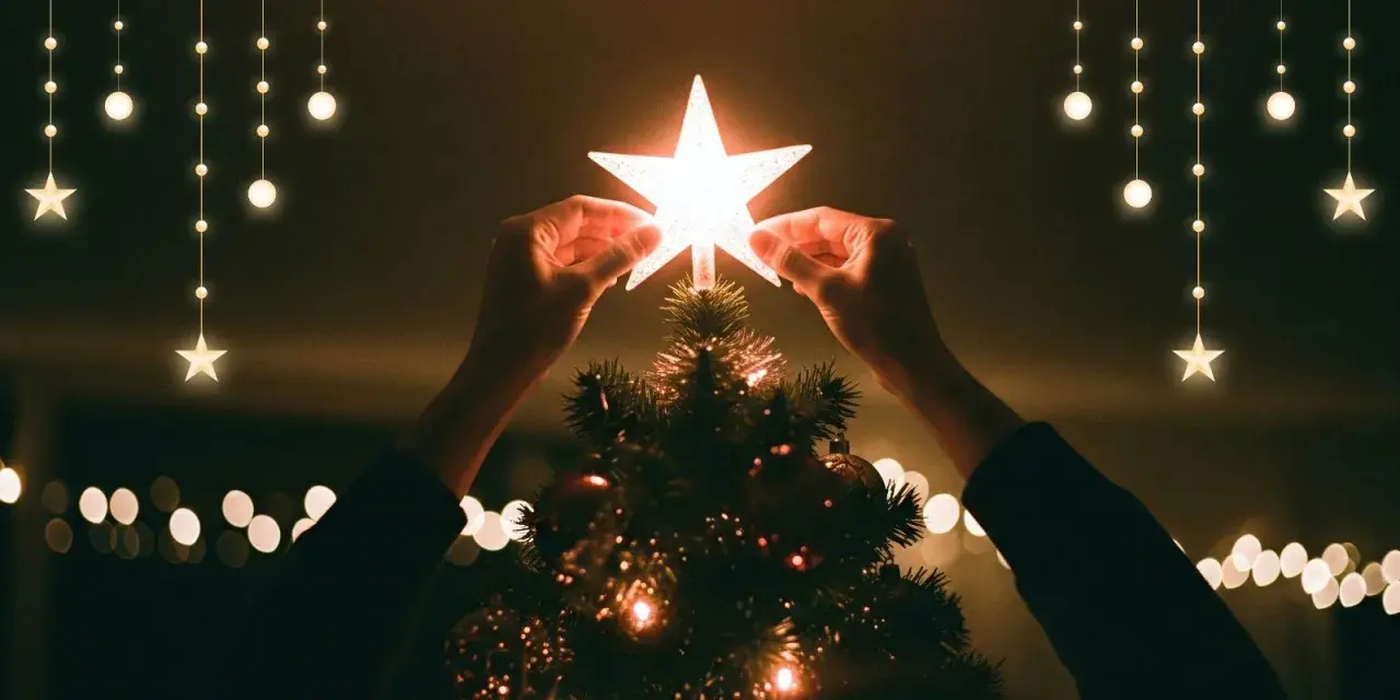 Hände setzen einen leuchtenden Stern auf die Spitze eines Weihnachtsbaums, der die weihnachtliche christliche Bedeutung des Lichts und der Hoffnung symbolisiert.