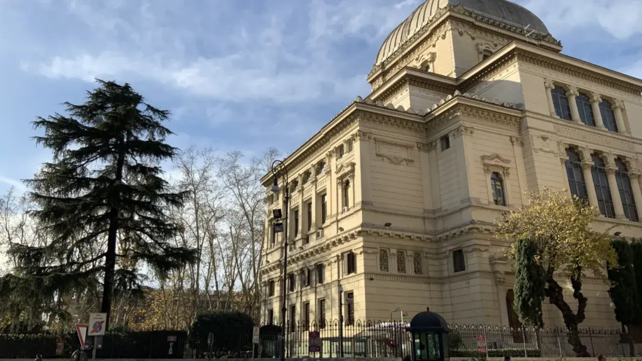 Grande Sinagoga e alberi nel quartiere ebraico di Roma, sotto un cielo azzurro con nuvole.