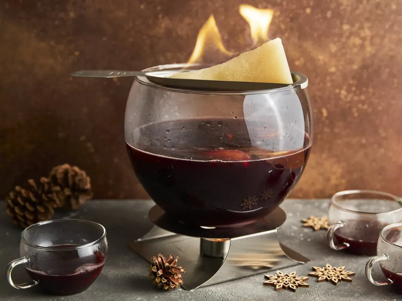 Alkoholfreie Feuerzangenbowle mit brennendem Zuckerhut und Gewürzen. Ein winterlicher Genuss für die ganze Familie.