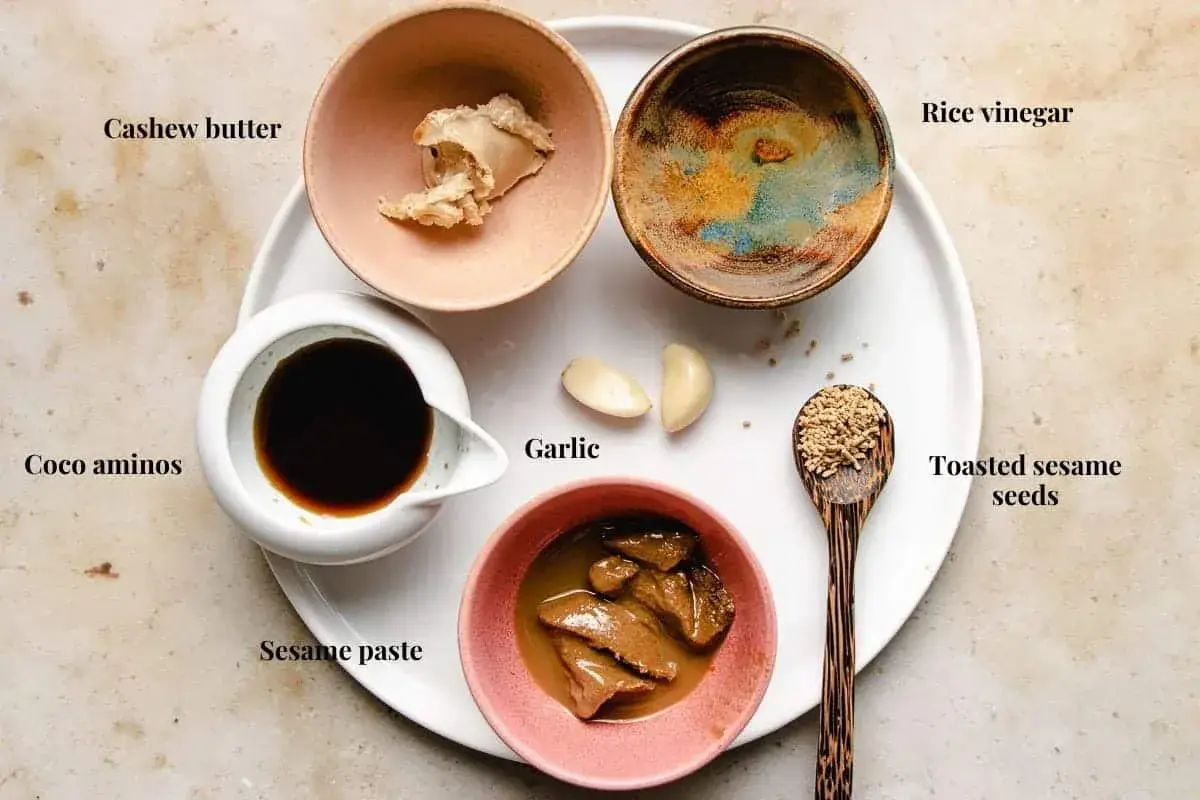 Ingredients for a delicious sesame sauce for hot pot: cashew butter, coco aminos, sesame paste, garlic, rice vinegar, and toasted sesame seeds.