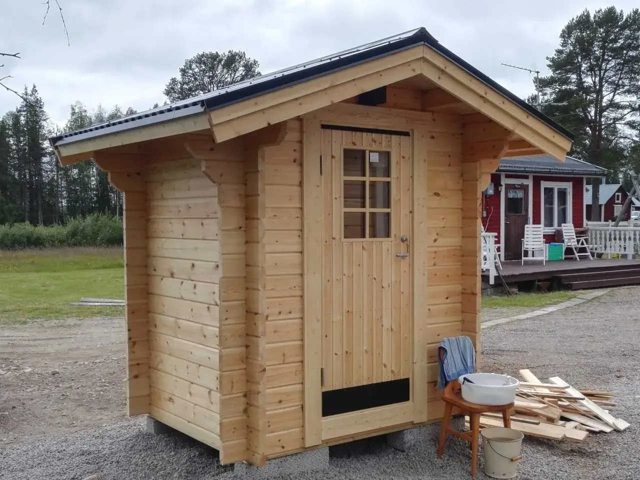 Nybyggt utedass i trä, redo att användas. Enkla verktyg och material ligger redo för att bygga utedass.