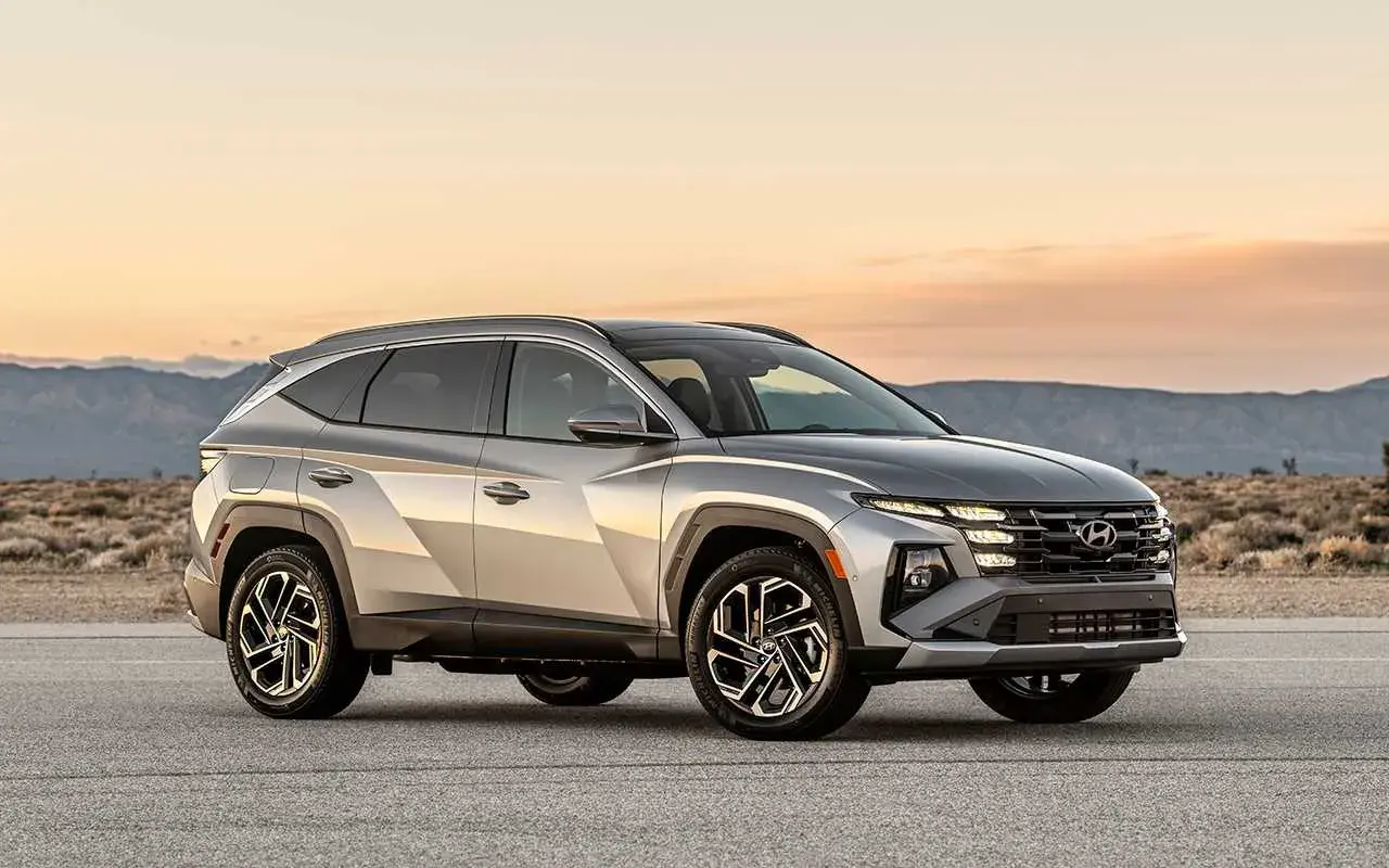 Silver Hyundai Tucson Hybrid testbil parkerad på en väg med berg i bakgrunden.