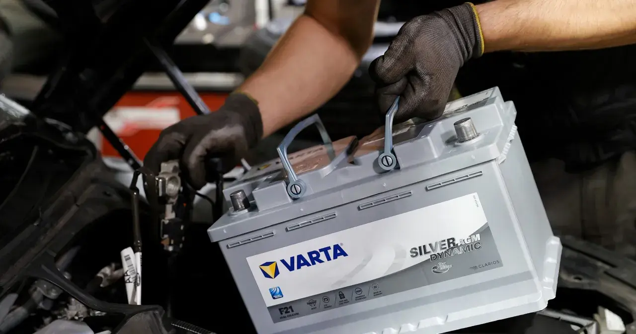 Mechanik w rękawiczkach wymienia akumulator Varta Silver AGM Dynamic, dbając o jego żywotność.