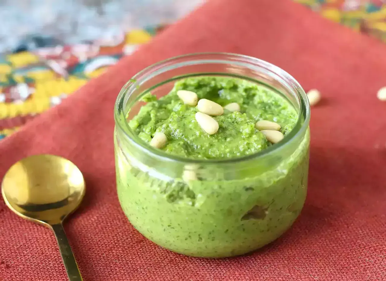 Un frasco de pesto casero, perfecto para tu próxima pasta al pesto receta, adornado con piñones.