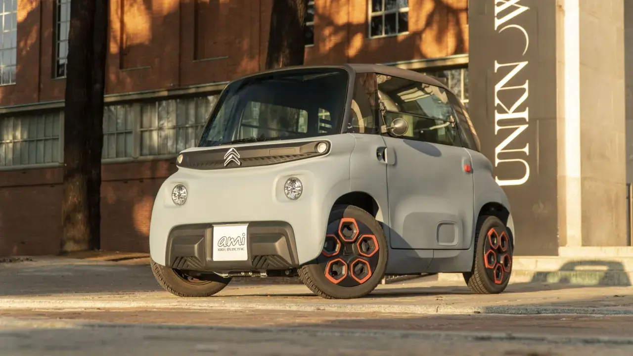 Citroën Ami, un veicolo elettrico compatto, mostra le sue prestazioni urbane con un design audace e ruote arancioni.