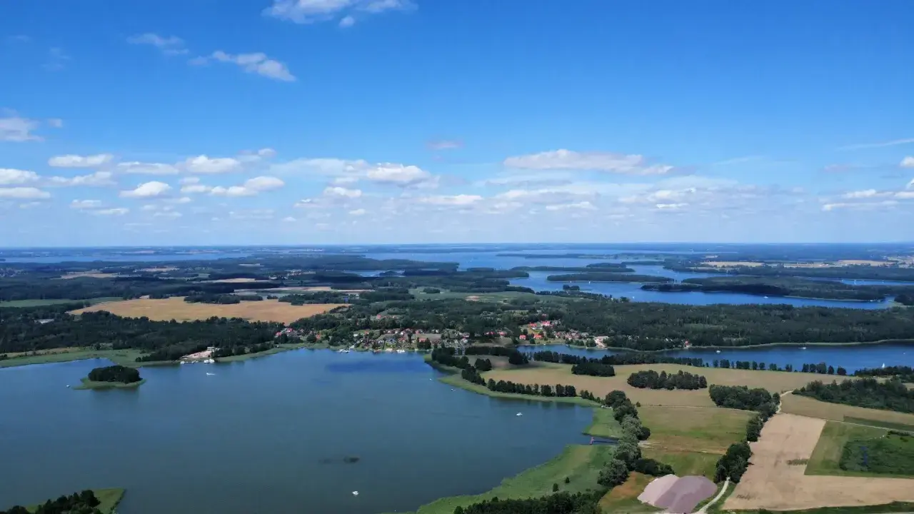 Krajobraz z lotu ptaka, gdzie widać liczne jeziora i lasy, tworzące malowniczą krainę tysiąca jezior.