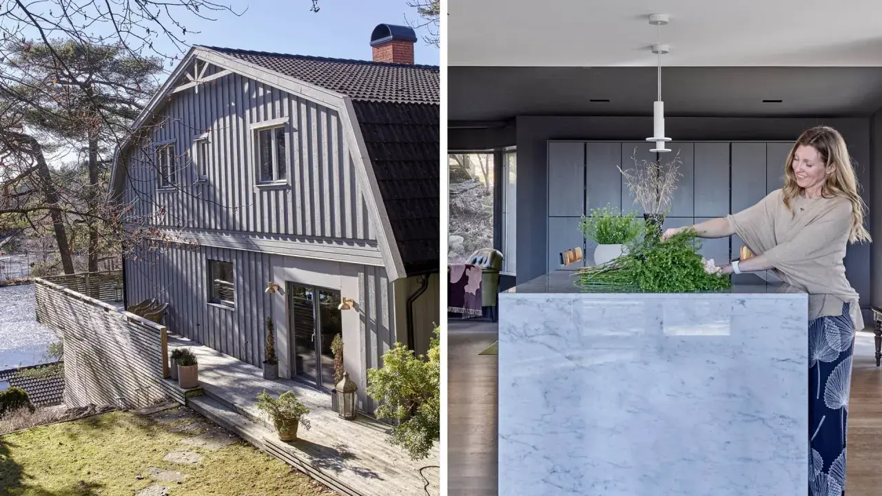 Ett grått egnahemshus från 40-talet med träfasad och altan vid vattnet. I köket arrangerar en kvinna grönska på en marmorö.