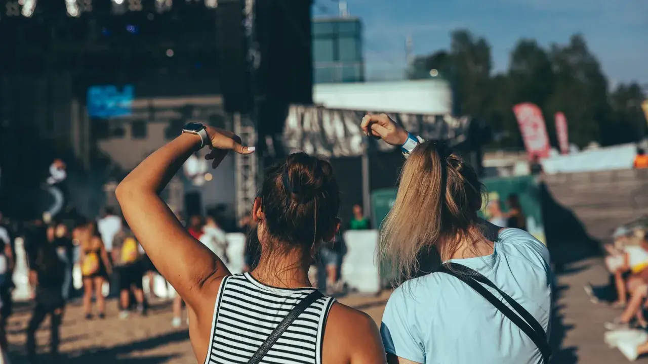 Dwie dziewczyny bawią się na koncercie podczas zielonego festiwalu, unosząc ręce w rytm muzyki.