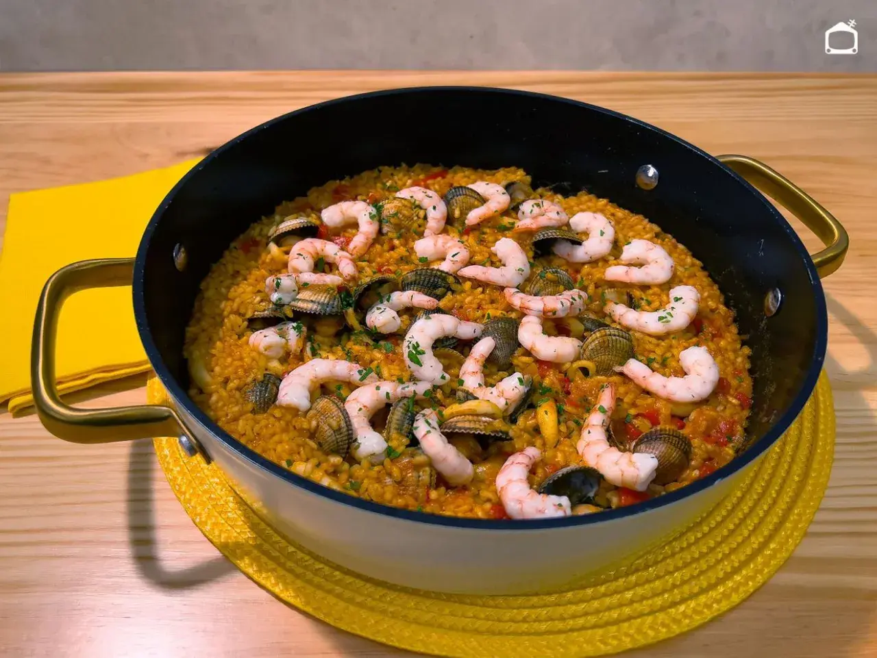Arroz con gambones y almejas en paellera, listo para disfrutar.