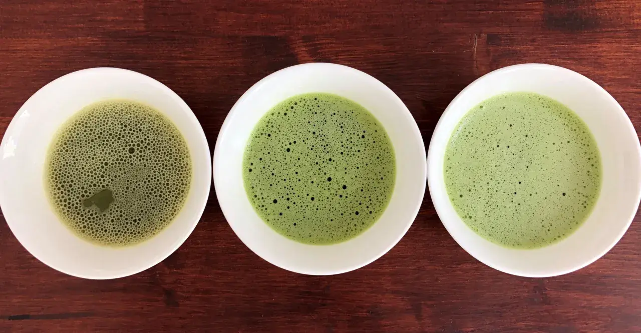 Drei Schalen mit schaumigem Matcha in verschiedenen Grüntönen, von hellgrün bis tiefgrün.