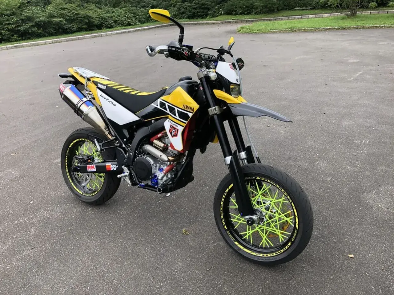 Yamaha WR 250 X personalizada con rines de radios amarillos brillantes y escape deportivo.