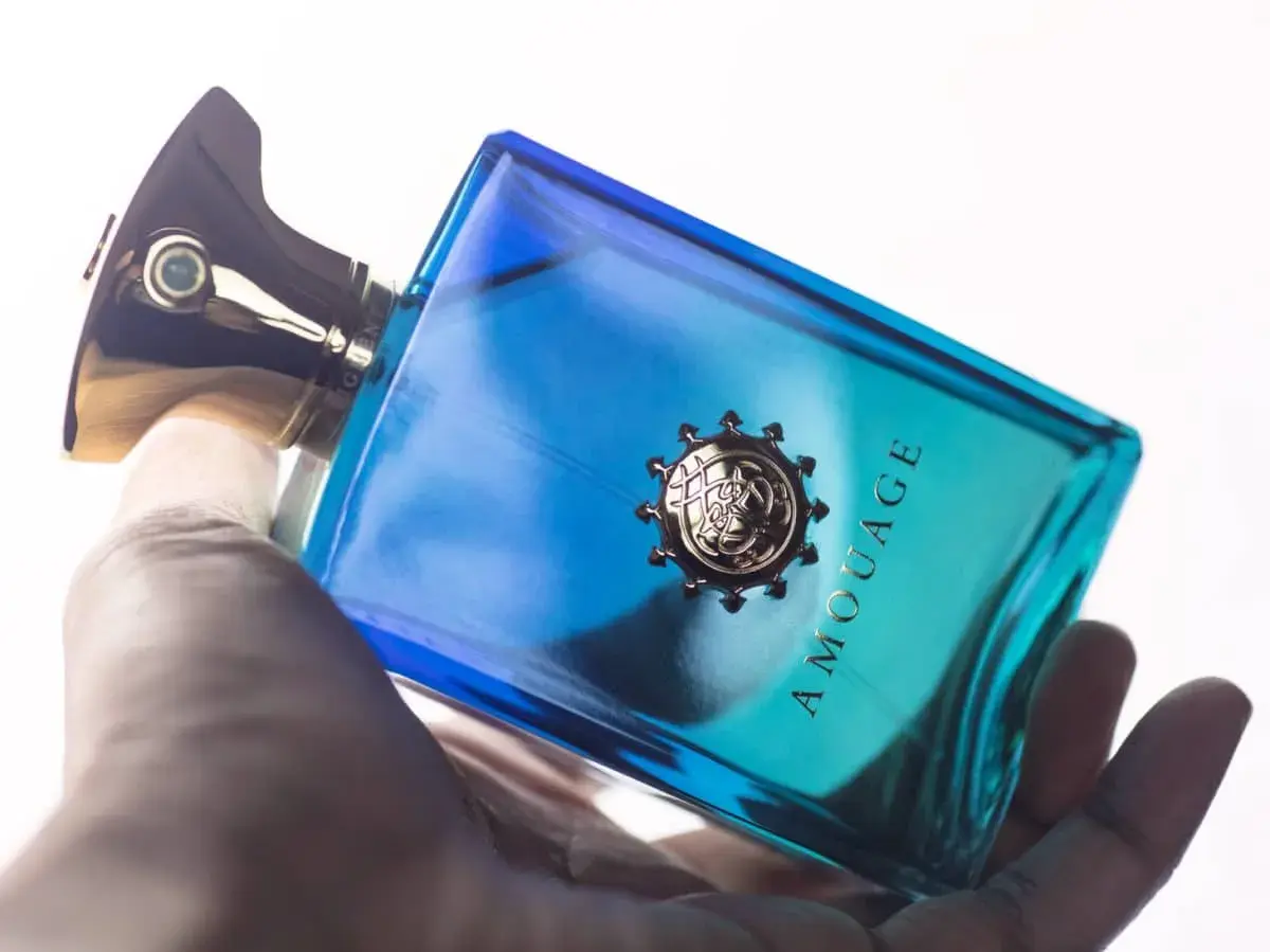 Dłoń trzyma luksusowe perfumy Amouage Figment w niebiesko-turkusowej butelce.