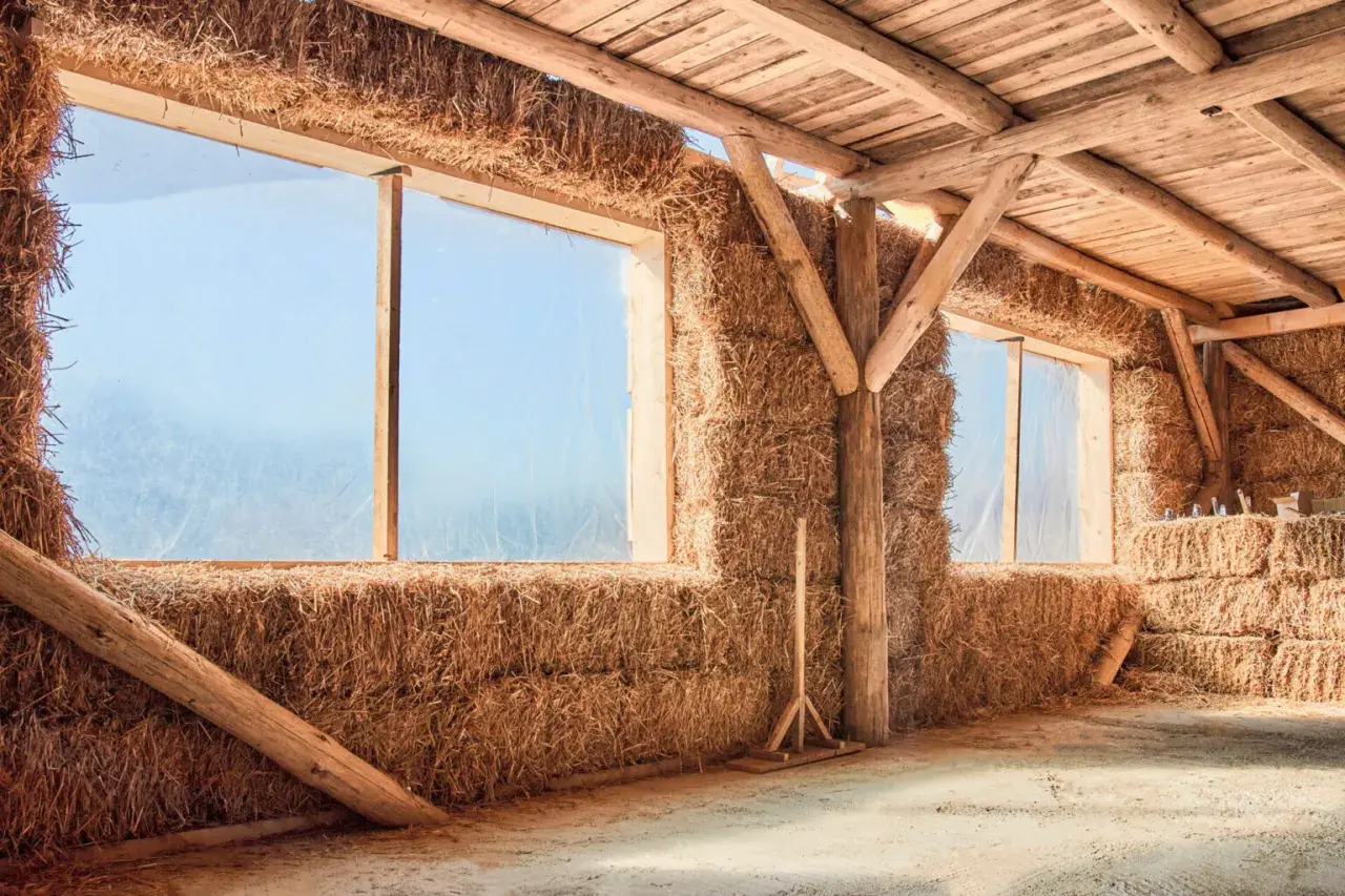 Interno di una struttura con pareti di balle di fieno e tetto in legno. Un esempio di costruzione con materiali ecosostenibili.