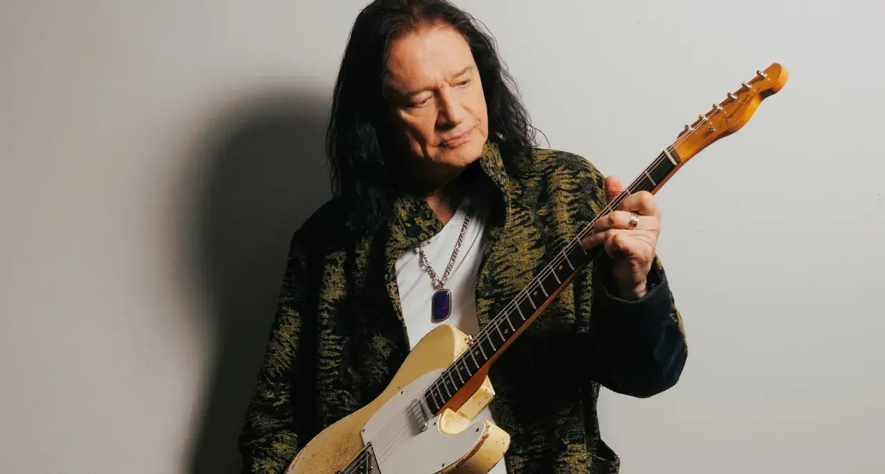 Musician Todd Rundgren, with his signature long dark hair, holds a vintage Fender Telecaster. His career has undoubtedly contributed to his impressive reb beach net worth.