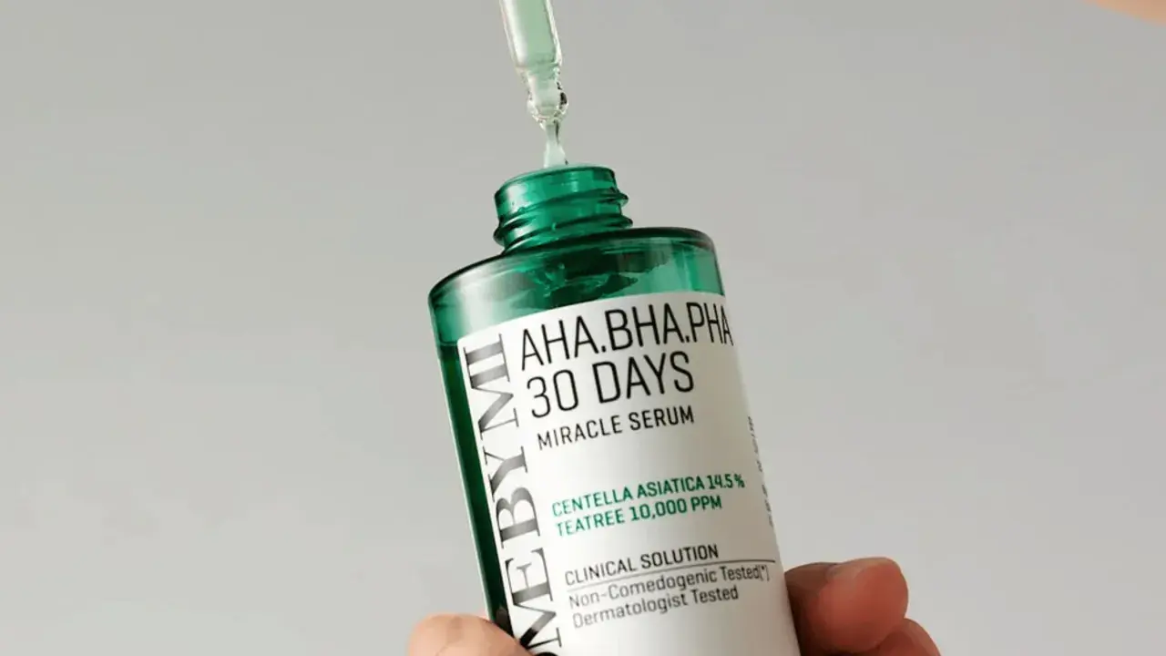 En droppe serum från en pipett landar på en flaska med "AHA.BHA.PHA 30 DAYS MIRACLE SERUM", en effektiv hudvård mot akne.