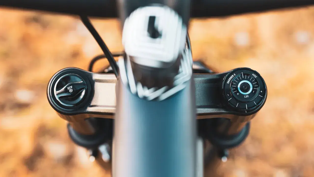 Close-up of a RockShox Pike fork's top caps, showing the "AIR" and "CHARGER 3" adjustments. The weight of this fork is a key factor for trail riders.