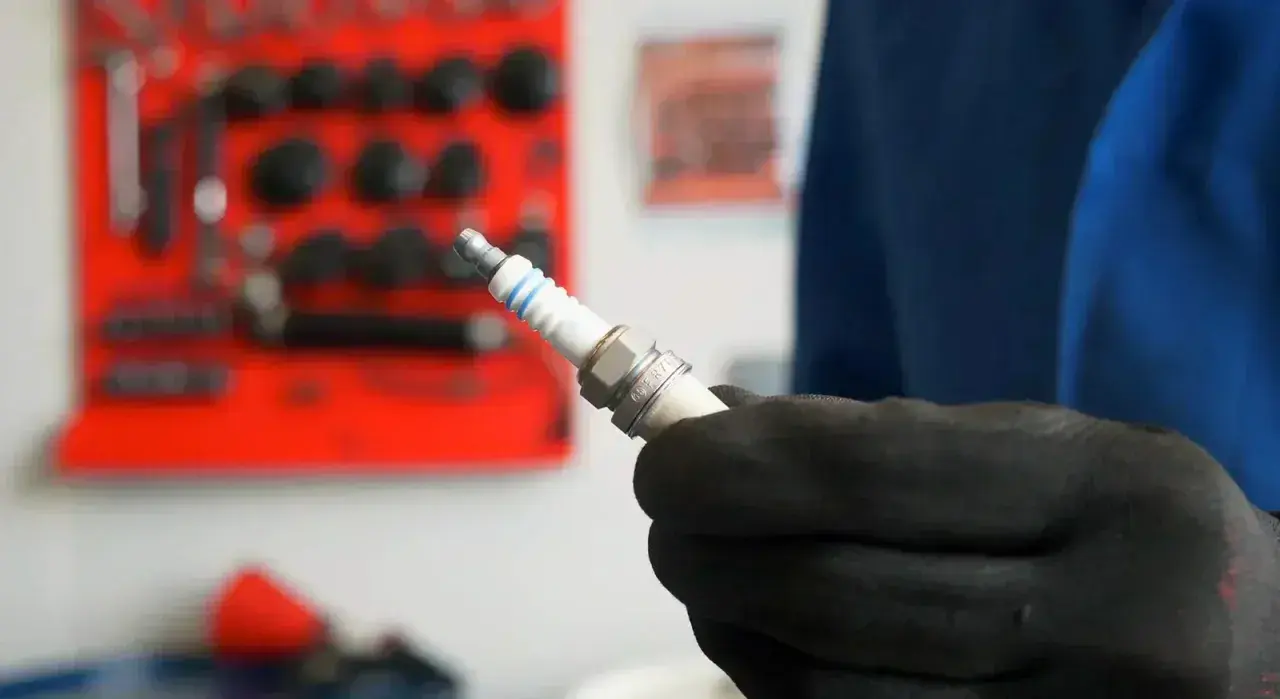 Main tenue une bougie d'allumage neuve, prête à être installée. Savoir quand changer les bougies d'allumage est essentiel pour le bon fonctionnement de votre moteur.