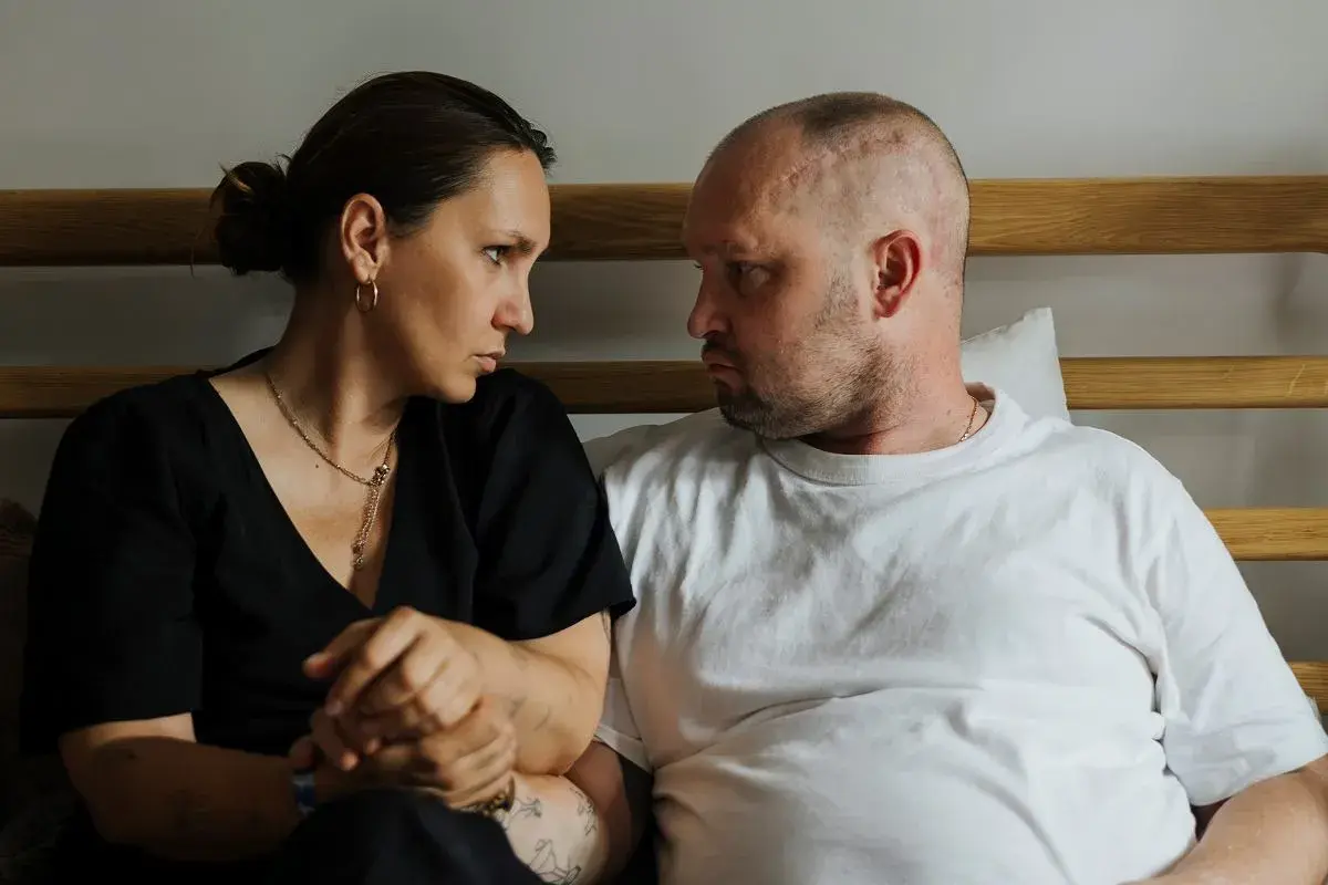 Anna Hernik i jej partner patrzą na siebie z powagą, siedząc obok siebie.