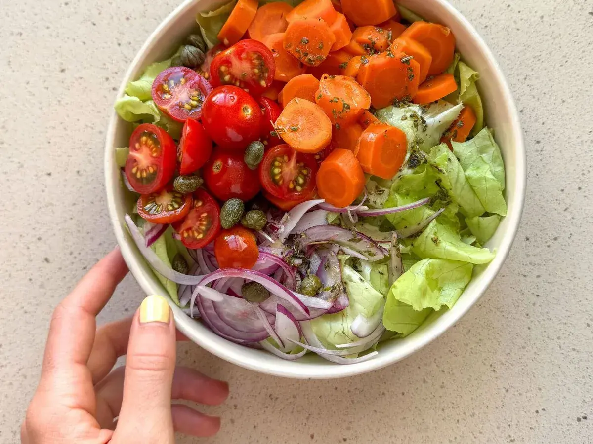 Deliciosa ensalada mediterránea con lechuga, tomates cherry, zanahoria, cebolla morada y alcaparras.