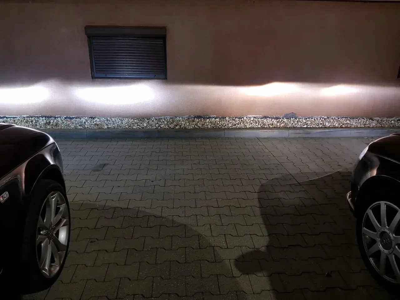 Jasne światła z przodu Audi A4 B6 oświetlają ścianę.