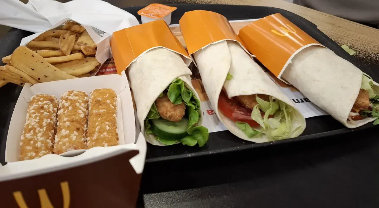 Trzy mcwrap klasyczny z kurczakiem, warzywami i sosem. Obok frytki i paluszki serowe. Idealny zestaw na szybki posiłek, z uwzględnieniem kcal.