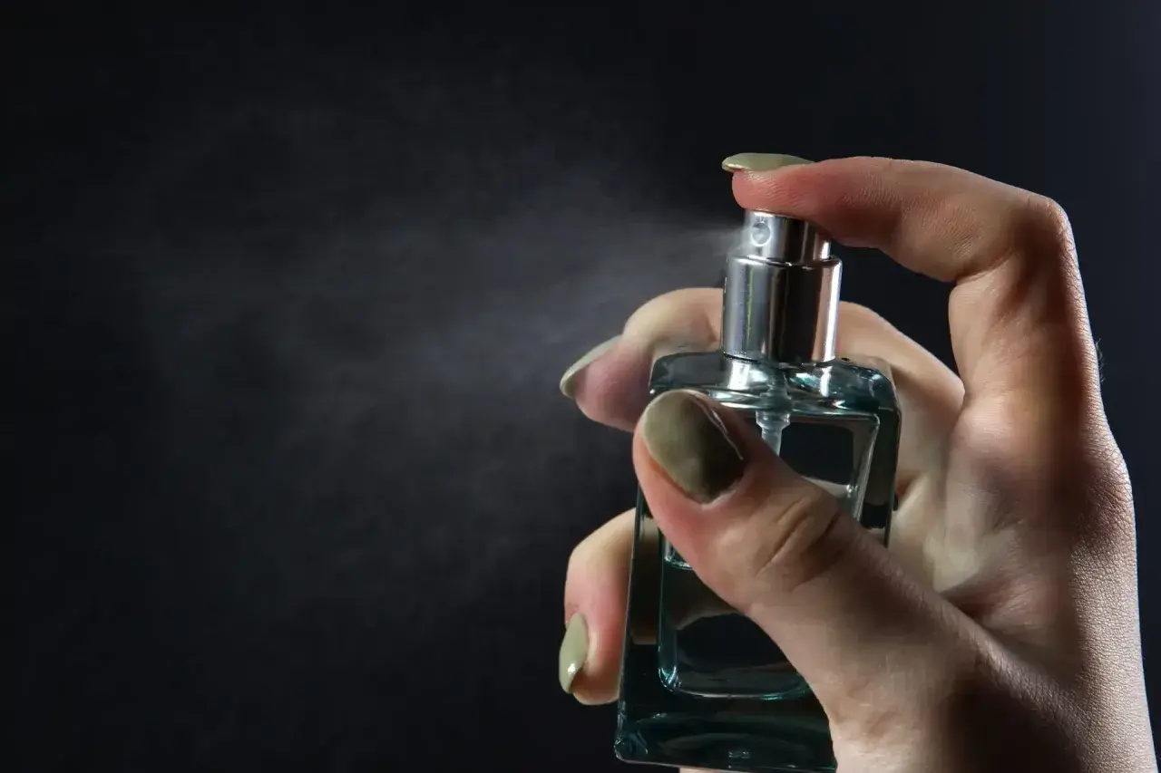 Dłoń rozpyla perfumy. Chcesz wiedzieć, jak sprawdzić, czy perfumy są oryginalne? Zwróć uwagę na detale flakonu i zapach.