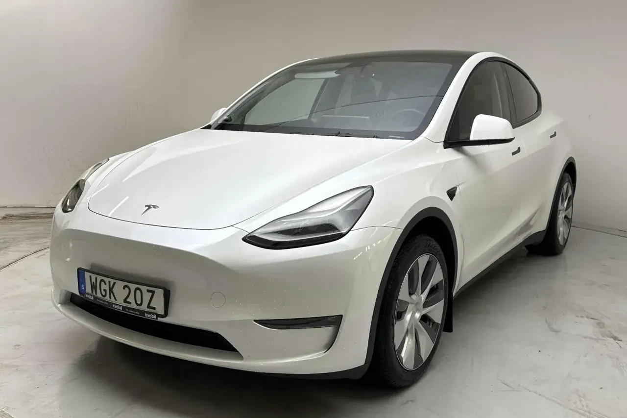 Vit Tesla Model Y, en begagnad elbil med mörk taklucka och stilrena fälgar. Perfekt för den miljömedvetna föraren.