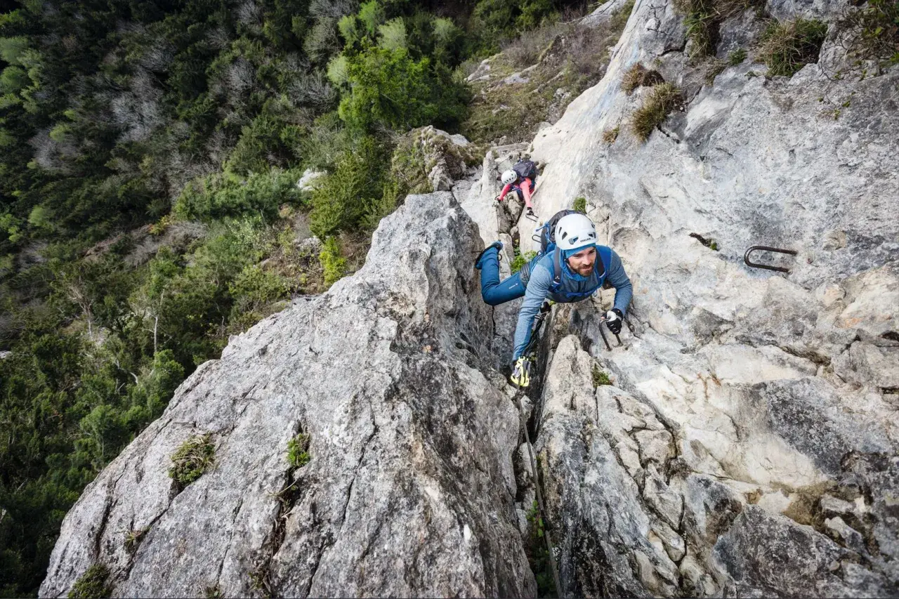 Mann klettert gesichert im Klettersteig, die Rastschlinge ist am Gurt befestigt.