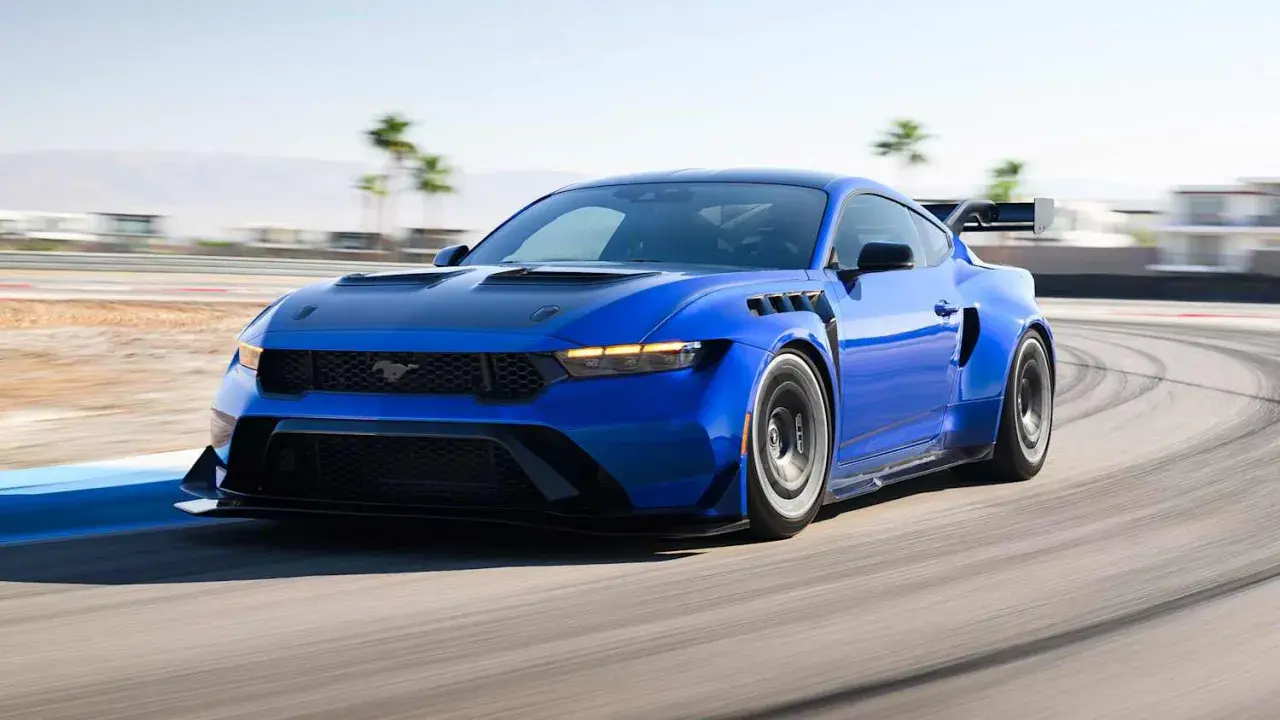 Blauer Mustang GTD rast auf Rennstrecke, mit breiten Kotflügeln und großem Heckspoiler.
