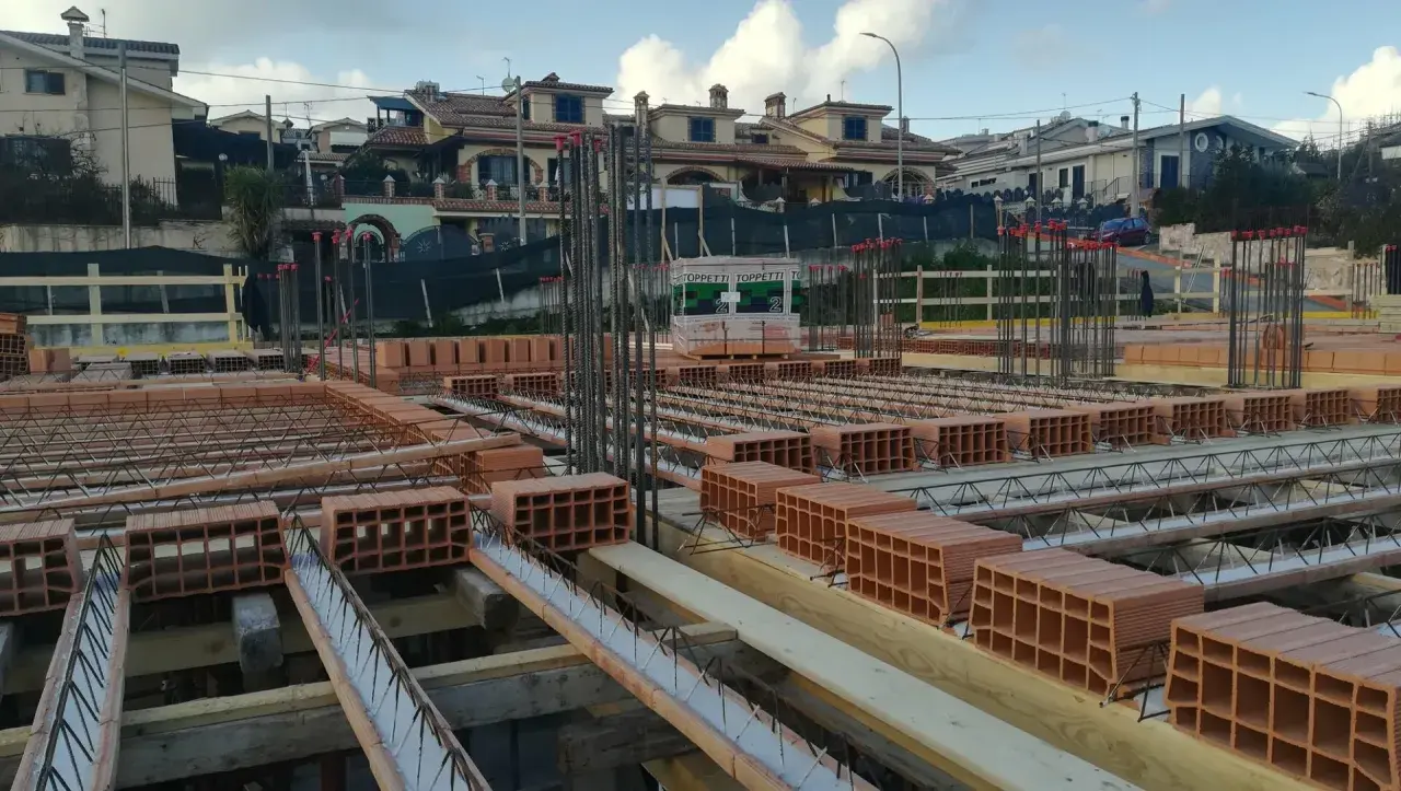 Cantiere edile con mattoni e armature in vista. Si sta preparando il miglior isolante termico per soffitto, con blocchi di laterizio pronti per la posa.