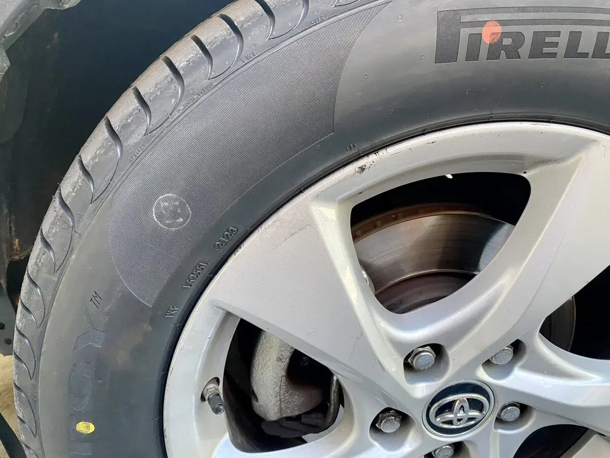 Un neumático Pirelli con un punto amarillo, marca de fábrica, y un pequeño círculo con una cara sonriente en el flanco.