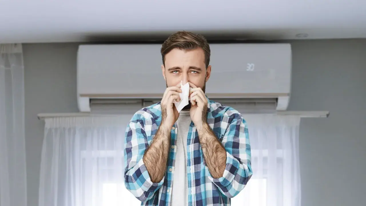 Hombre con pañuelo en la nariz, con aire acondicionado de fondo. Podría ser que se puede tener alergia al aire acondicionado.