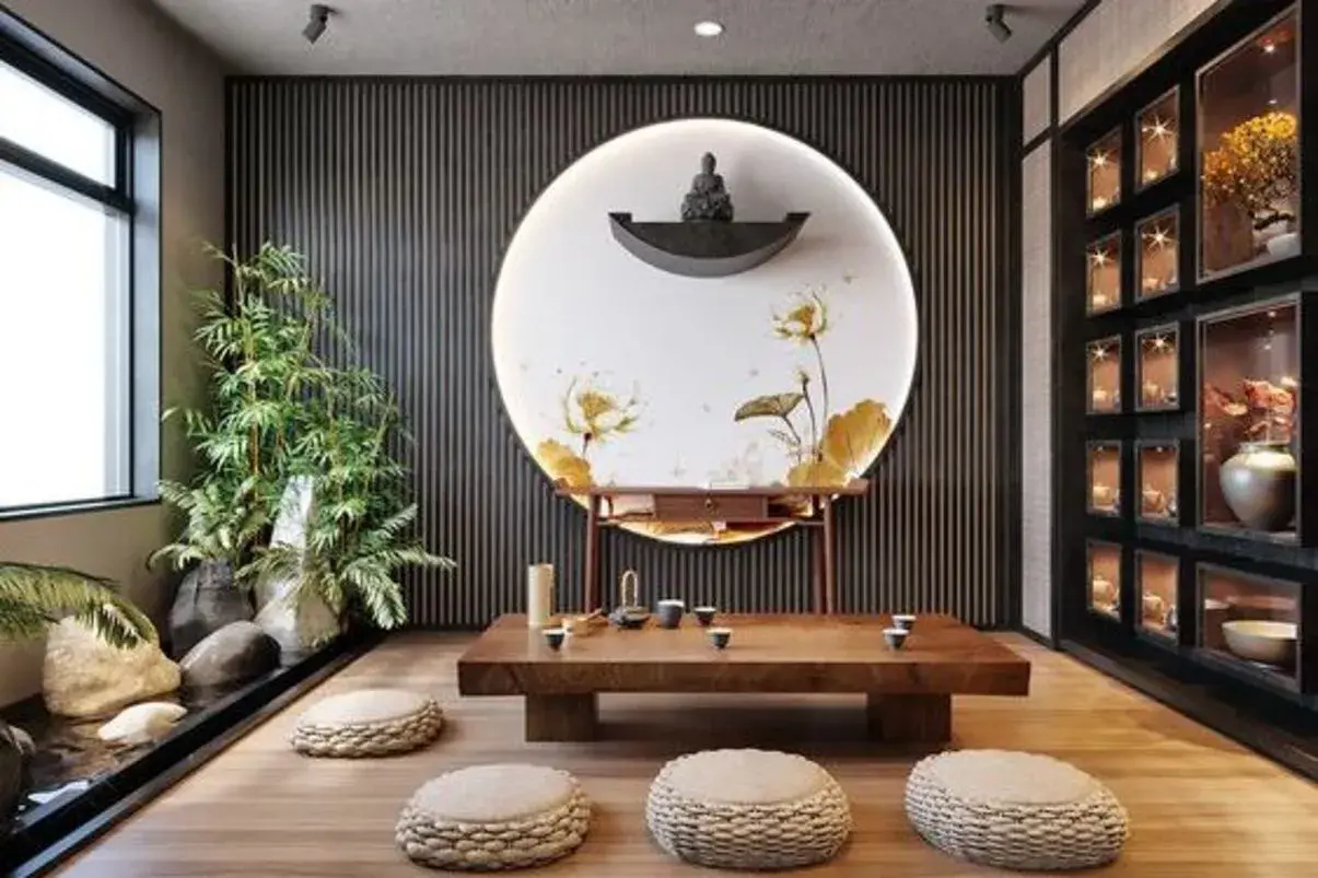 Ein Raum im japanischen Einrichtungsstil mit einem niedrigen Holztisch, Sitzkissen, einer Buddha-Statue auf einem Podest und einem Wandbild mit Lotusblumen.